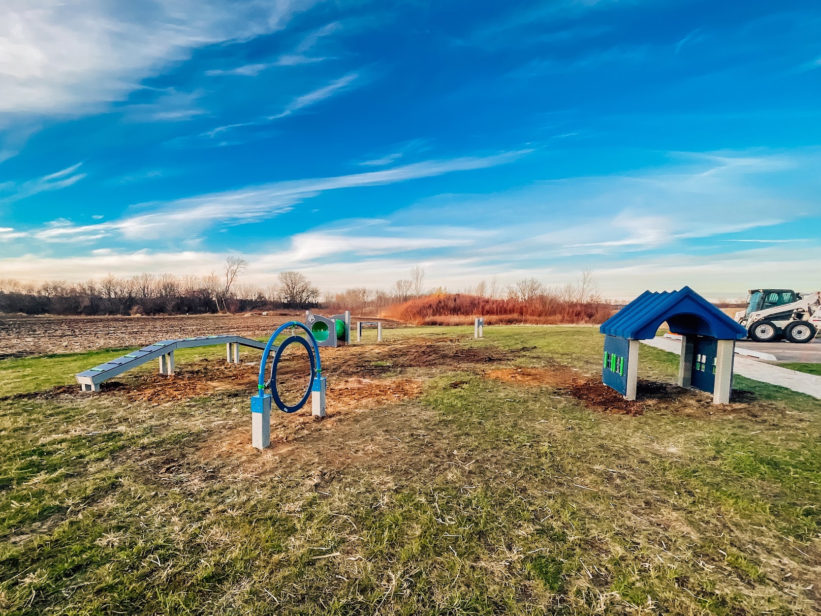 Wide view of a newly installed commercial dog park with agility equipment in Kenosha, Wisconsin.