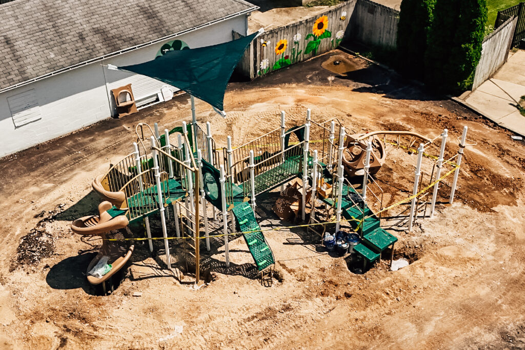 Aerial drone view of a newly installed playground in Troy, Ohio, featuring slides, monkey bars, rock climber, and shade structure.