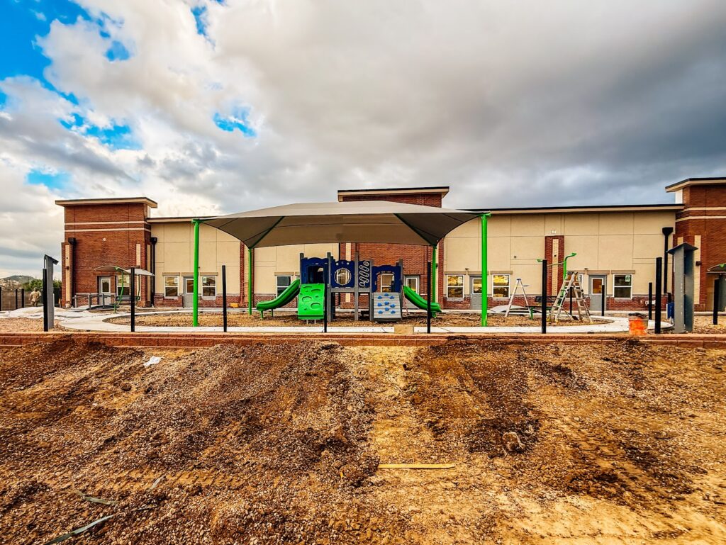 Full view of the new playground at Kiddie Academy in Castle Rock, Colorado, featuring play structures, shade, and imaginative play elements.